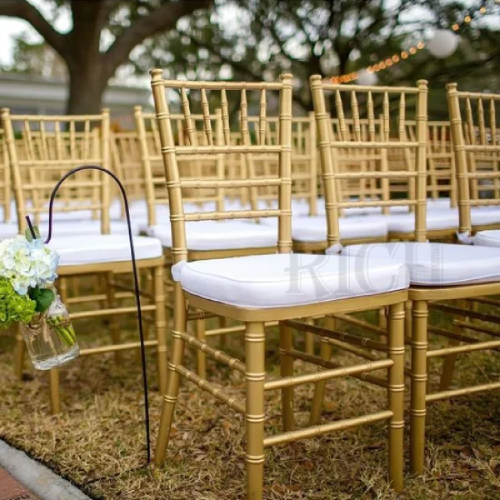 Close-up of gold chiavari chair with padded ivory cushion showing spindle back detail