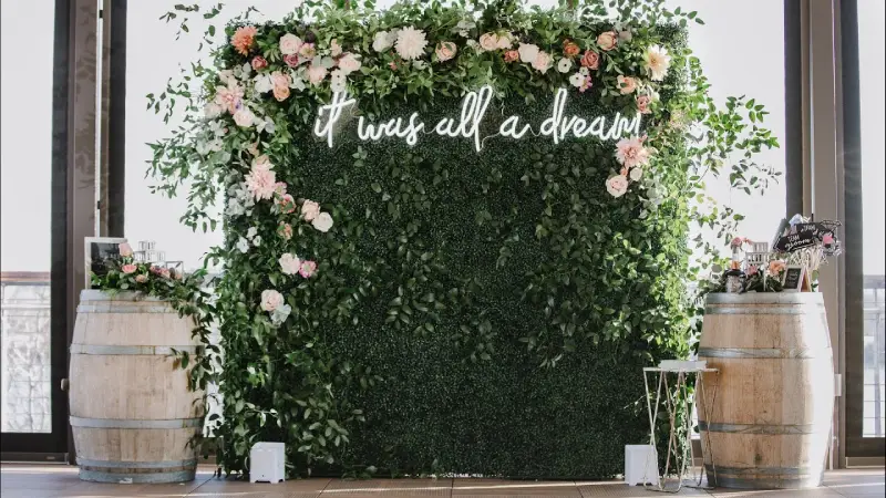 Wine barrel rental BC used as a floral wedding backdrop with greenery and romantic signage for an Okanagan event