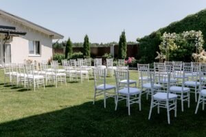 Elegant backyard wedding reception setup with white marquee tent, chiavari chairs, and string lights in the Okanagan