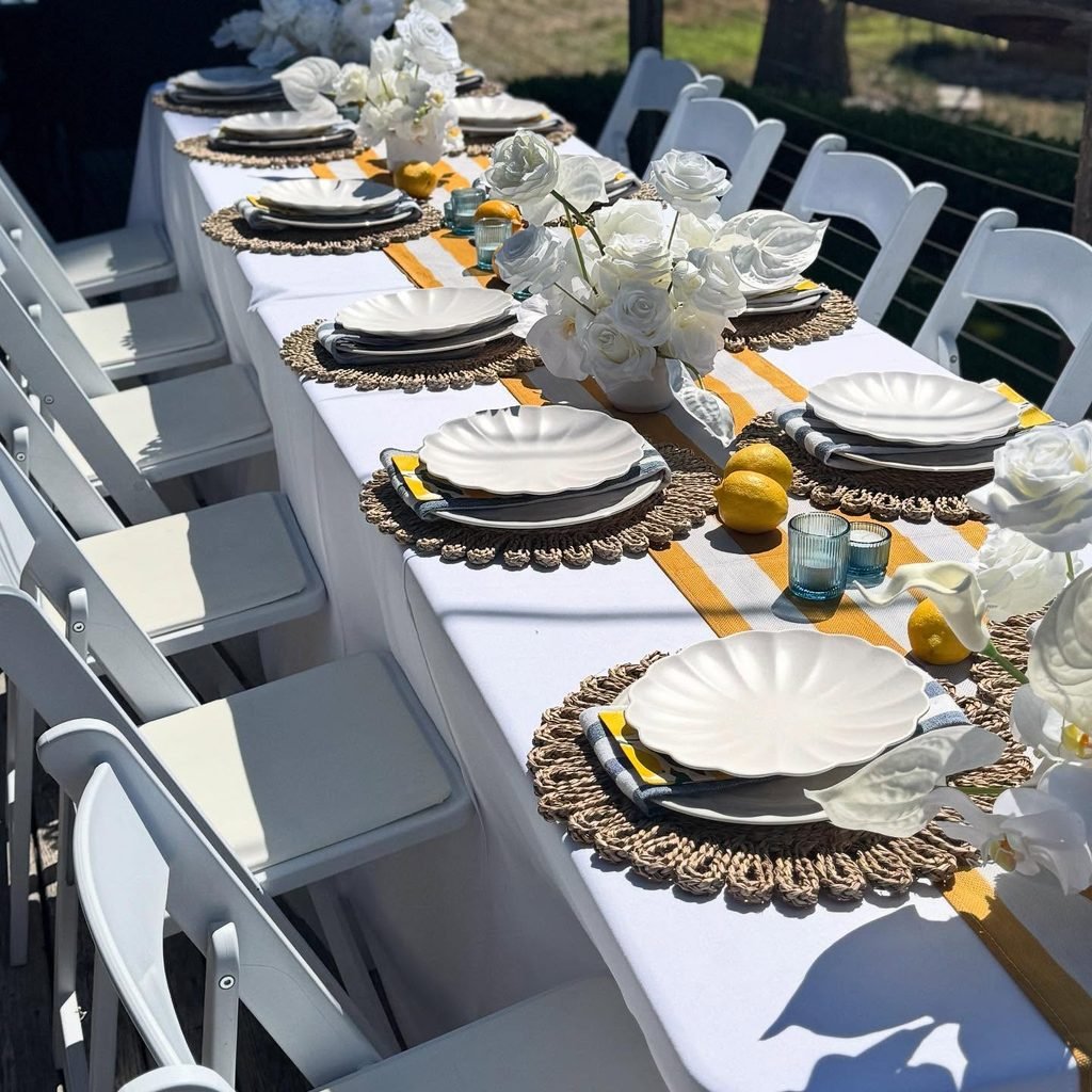 Rectangular banquet table with white folding chairs, white linens and floral centrepieces